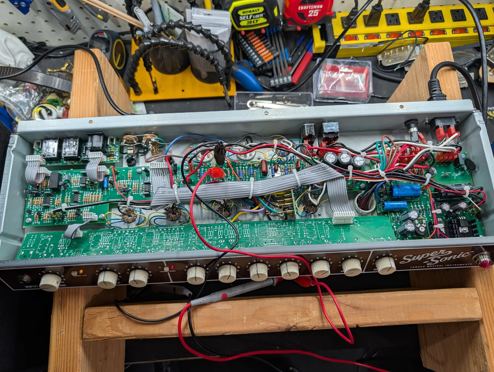 Open guitar amplifier chassis undergoing electronics service